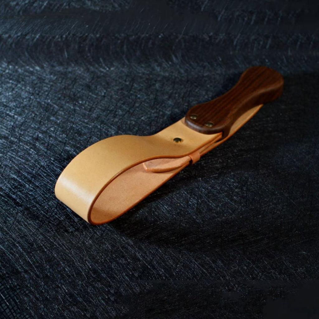 Natural tan leather paddle on dark surface – walnut wood handle gold rivet vegetable tanned BDSM spanking paddle
