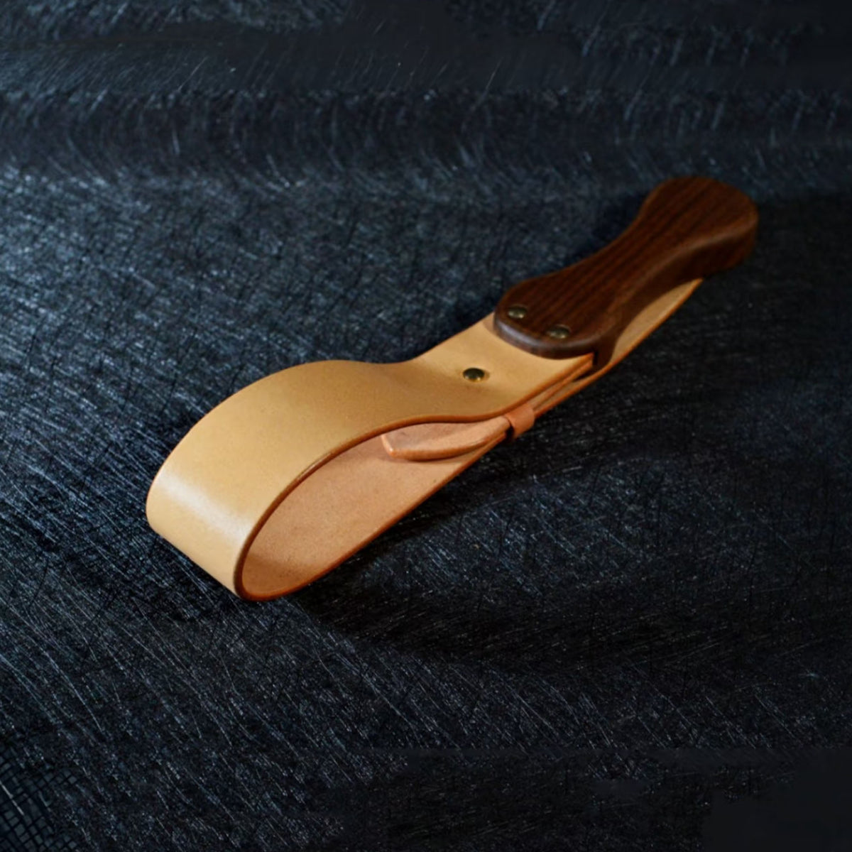 Natural tan leather paddle on dark surface – walnut wood handle gold rivet vegetable tanned BDSM spanking paddle
