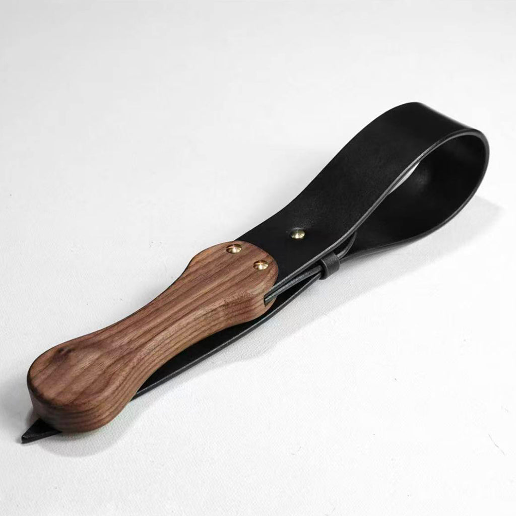 Black leather paddle with walnut wood handle on white background – gold rivet full grain cowhide BDSM handmade product
