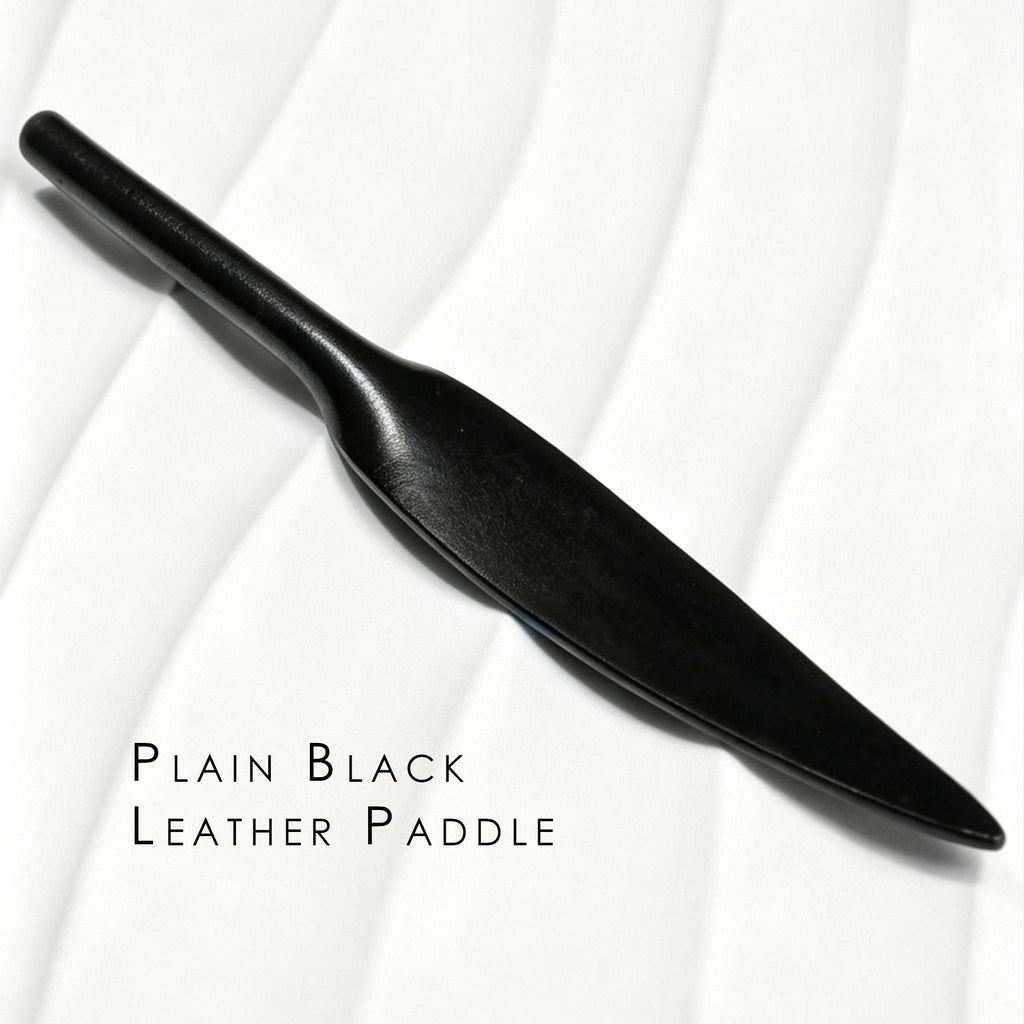 Plain black leather paddle on white background – smooth leaf blade tapered handle one-piece cowhide BDSM portable paddle
