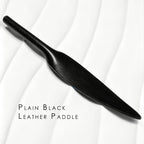 Plain black leather paddle on white background – smooth leaf blade tapered handle one-piece cowhide BDSM portable paddle

