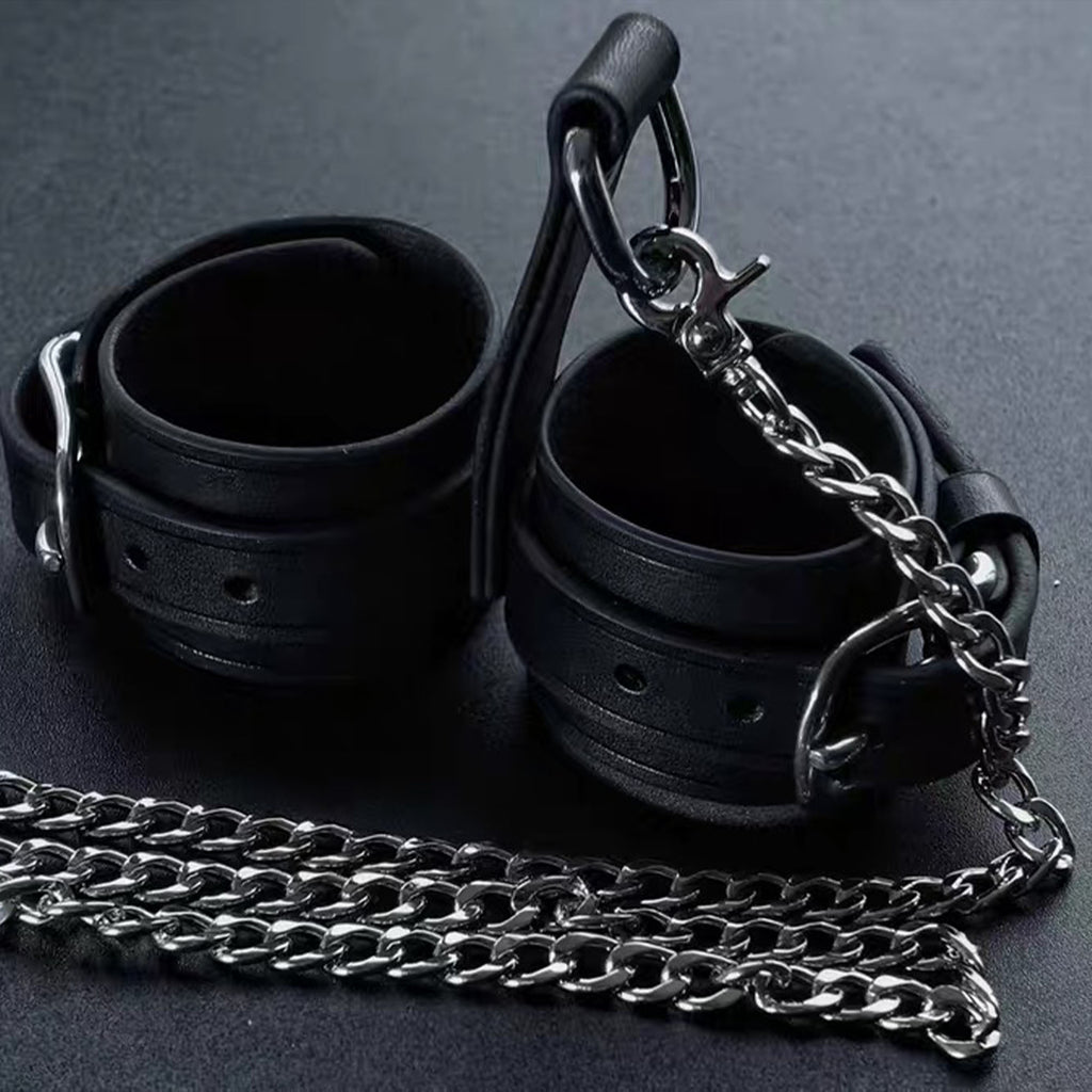 Black leather wrist cuffs pair with silver chain leash flat lay – buckle D-ring connector full set display

