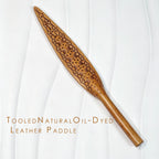 Natural oil-dyed tooled leather paddle on white background – intricate carved floral pattern leaf blade full view BDSM handmade
