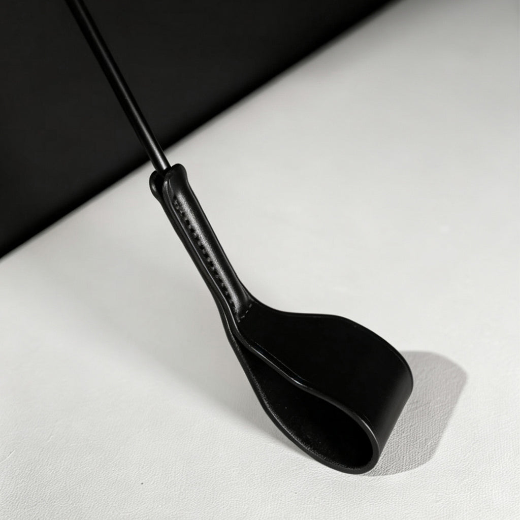 Black leather riding crop folded tip close-up – stitched neck connection vegetable tanned detail BDSM crop
