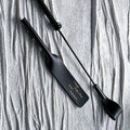 Black leather paddle and riding crop displayed together – vegetable tanned handmade BDSM impact play set product display
