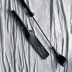 Black leather paddle and riding crop displayed together – vegetable tanned handmade BDSM impact play set product display
