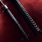 Black leather riding crop handle cross-stitch detail on red velvet – two crops handmade craftsmanship close-up
