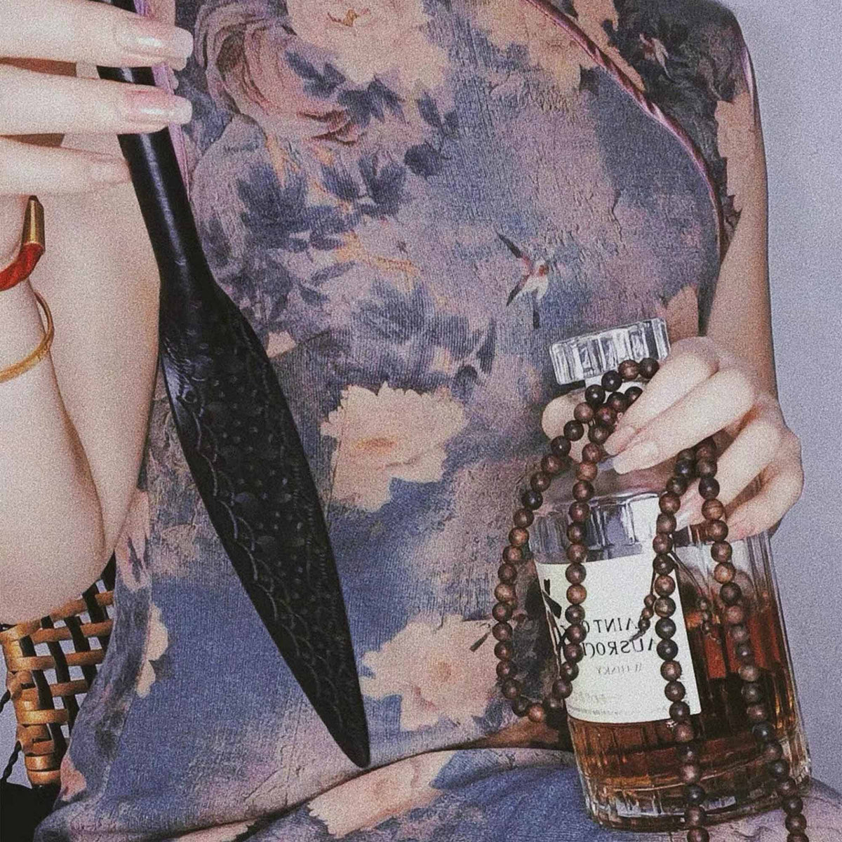 Black tooled leather paddle held in hand – intricate carved floral pattern leaf blade BDSM impact play lifestyle editorial

