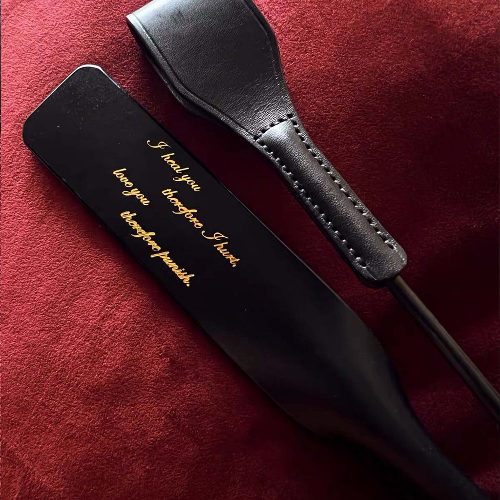 Two black leather riding crops side by side on red velvet – gold engraved text hand-stitched handle comparison display
