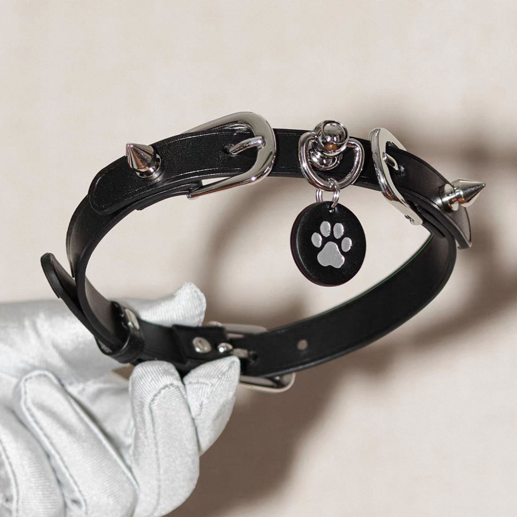 Black leather spiked choker front view in white gloved hands – silver square buckle O-ring custom charm pendant
