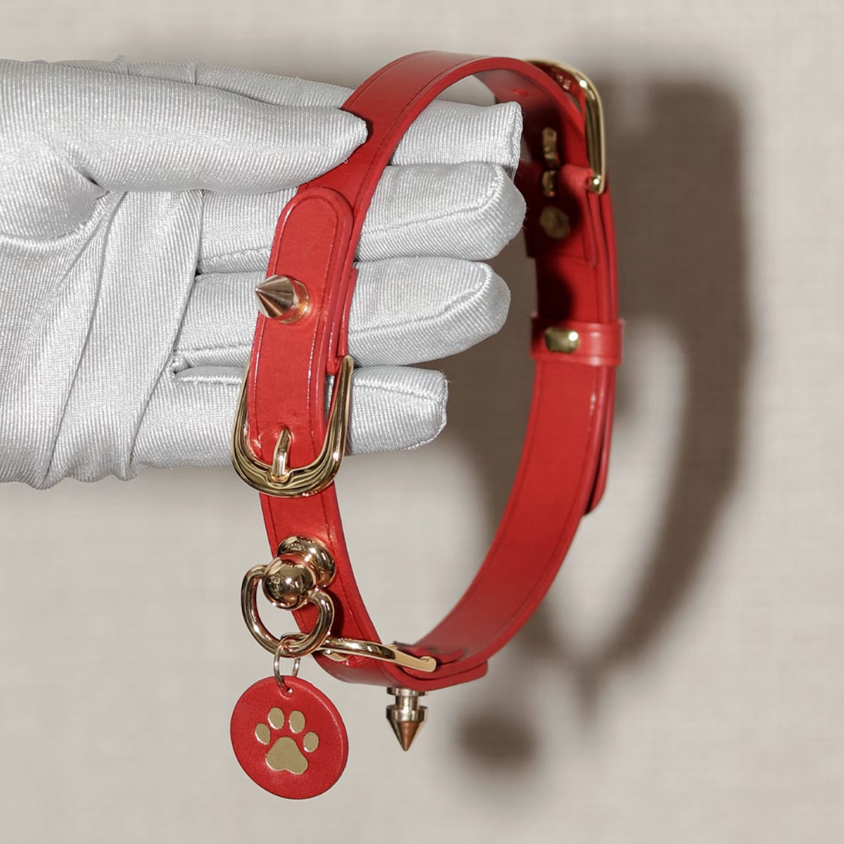 Red leather spiked choker hand-held close-up – gold cone rivets buckle custom charm detail handmade BDSM
