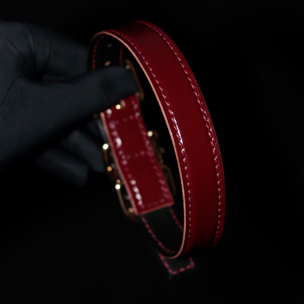 Burgundy leather BDSM collar side view – red hand-stitched natural leather edge gold hardware bell charm
