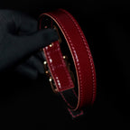 Burgundy leather BDSM collar side view – red hand-stitched natural leather edge gold hardware bell charm

