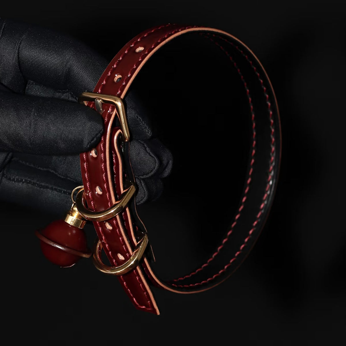 Burgundy leather BDSM collar buckle and D-ring close-up – gold hardware red bell natural leather edge hand-stitched
