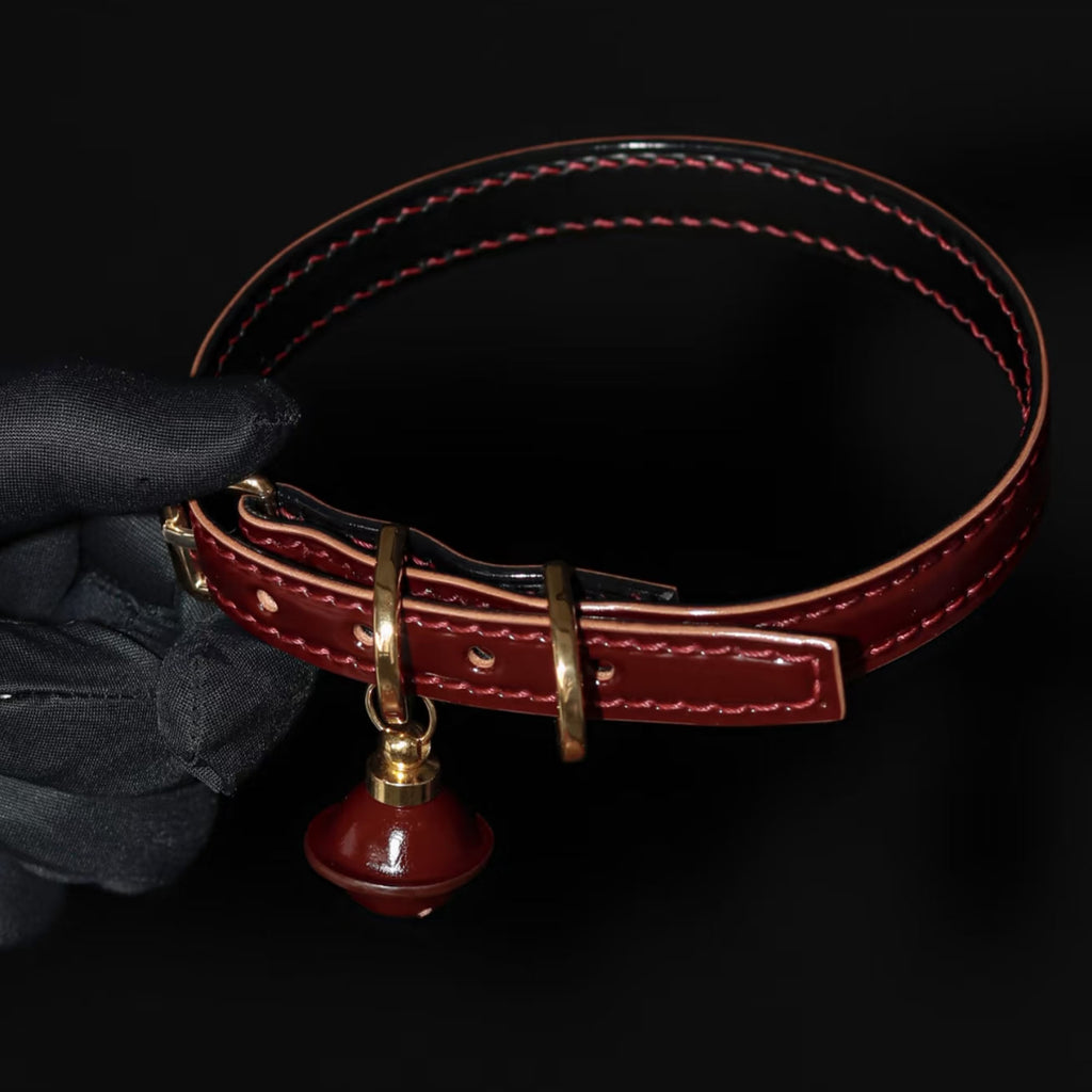 Burgundy leather BDSM collar side profile – red saddle stitching natural leather edge red bell charm gold hardware
