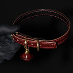 Burgundy leather BDSM collar side profile – red saddle stitching natural leather edge red bell charm gold hardware
