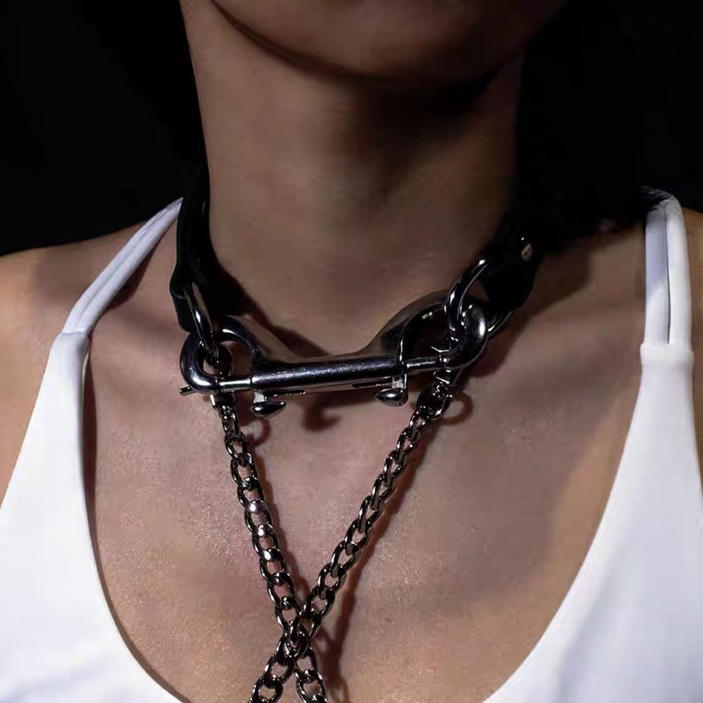 Detailed close-up of model wearing black leather collar connected horizontally with a silver double bolt snap and chain detail