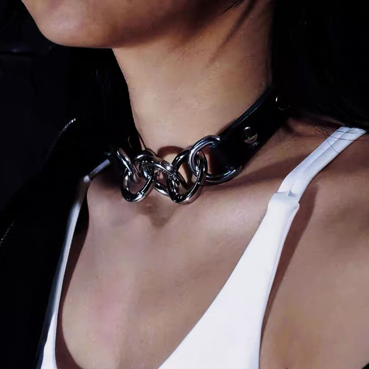Side profile view of model wearing black leather collar joined with three silver spring O-rings against the collarbone