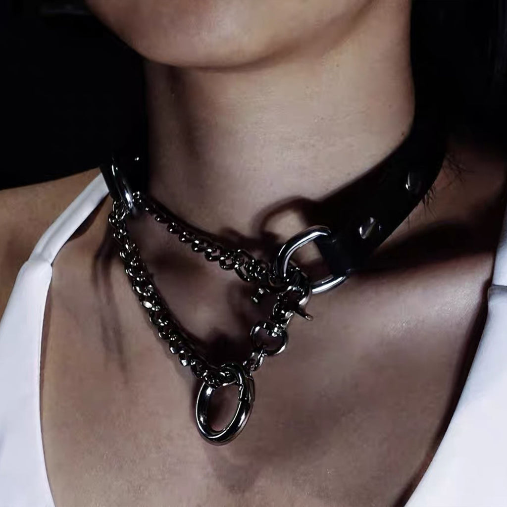 Close-up angle of model wearing black leather collar with asymmetrical draped silver curb chains and ring connector