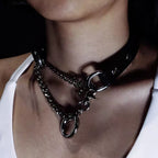 Close-up angle of model wearing black leather collar with asymmetrical draped silver curb chains and ring connector