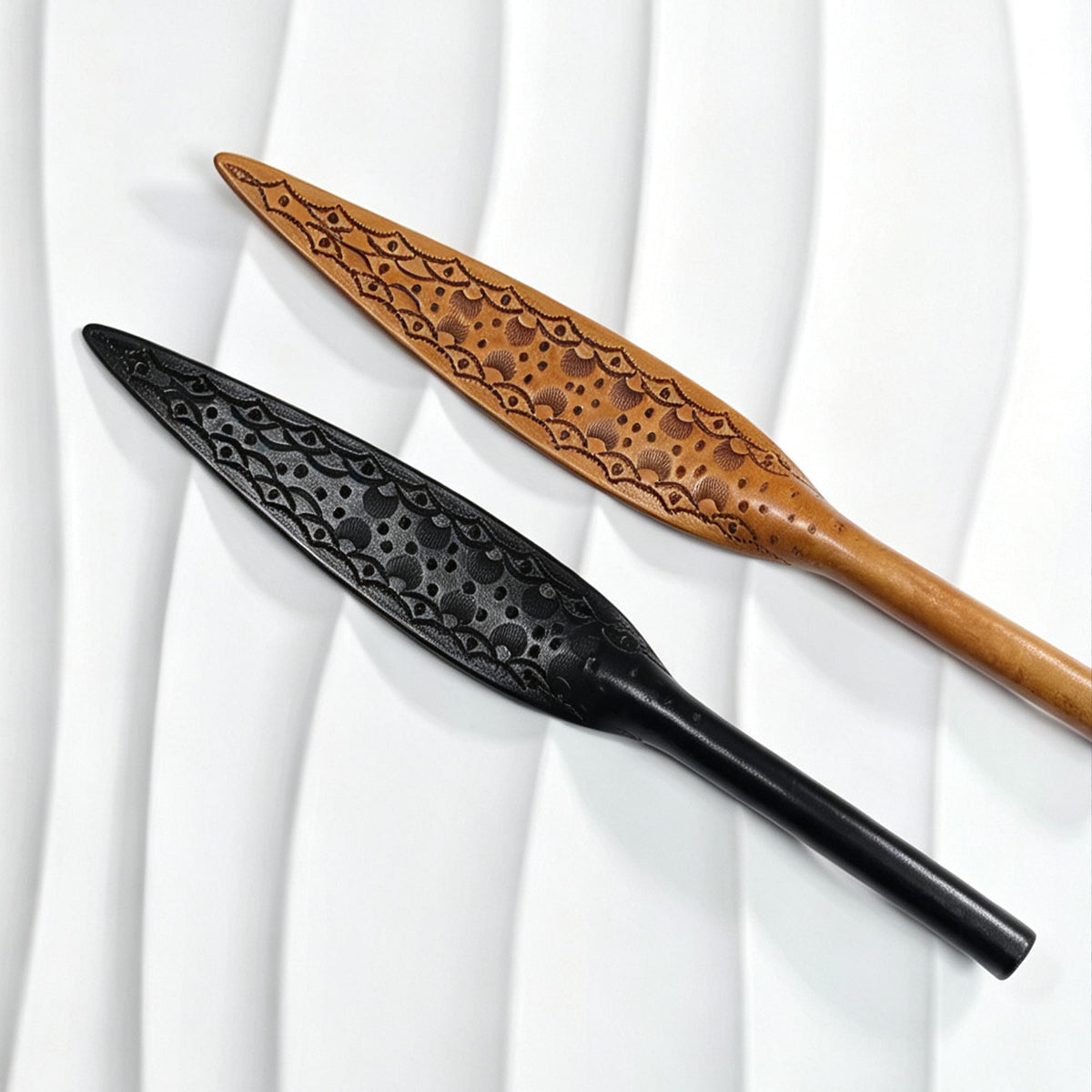 Black tooled and natural oil-dyed tooled leather paddles displayed together – intricate carved floral pattern leaf blade BDSM handmade comparison
